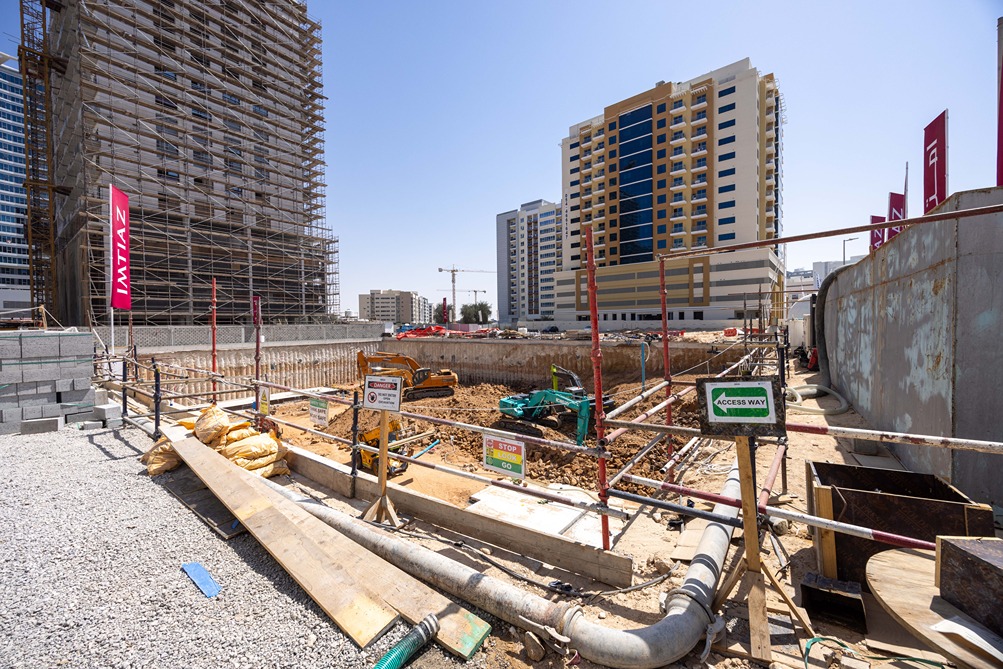 Cove Edition I By Imtiaz 1 Construction site with heavy machinery, scaffolding, and prominent buildings under development against a clear sky.
